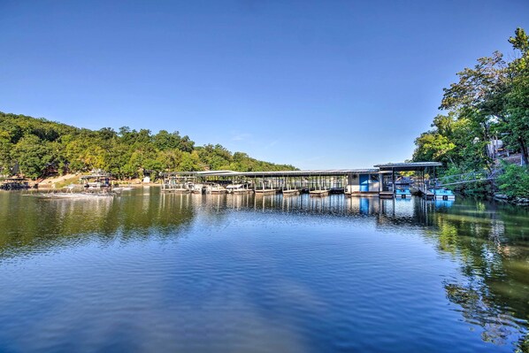 A calm lake with a dock and boats, surrounded by trees and hills. - Resort Villa on Lake of the Ozarks! Family Fun Hub (Osage Beach)