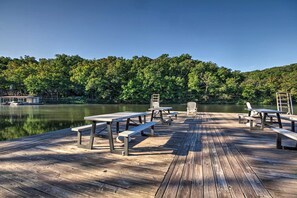 A wooden dock with picnic tables and benches overlooking a calm lake, surrounded by dense forest. - Resort Villa on Lake of the Ozarks! Family Fun Hub (Osage Beach)
