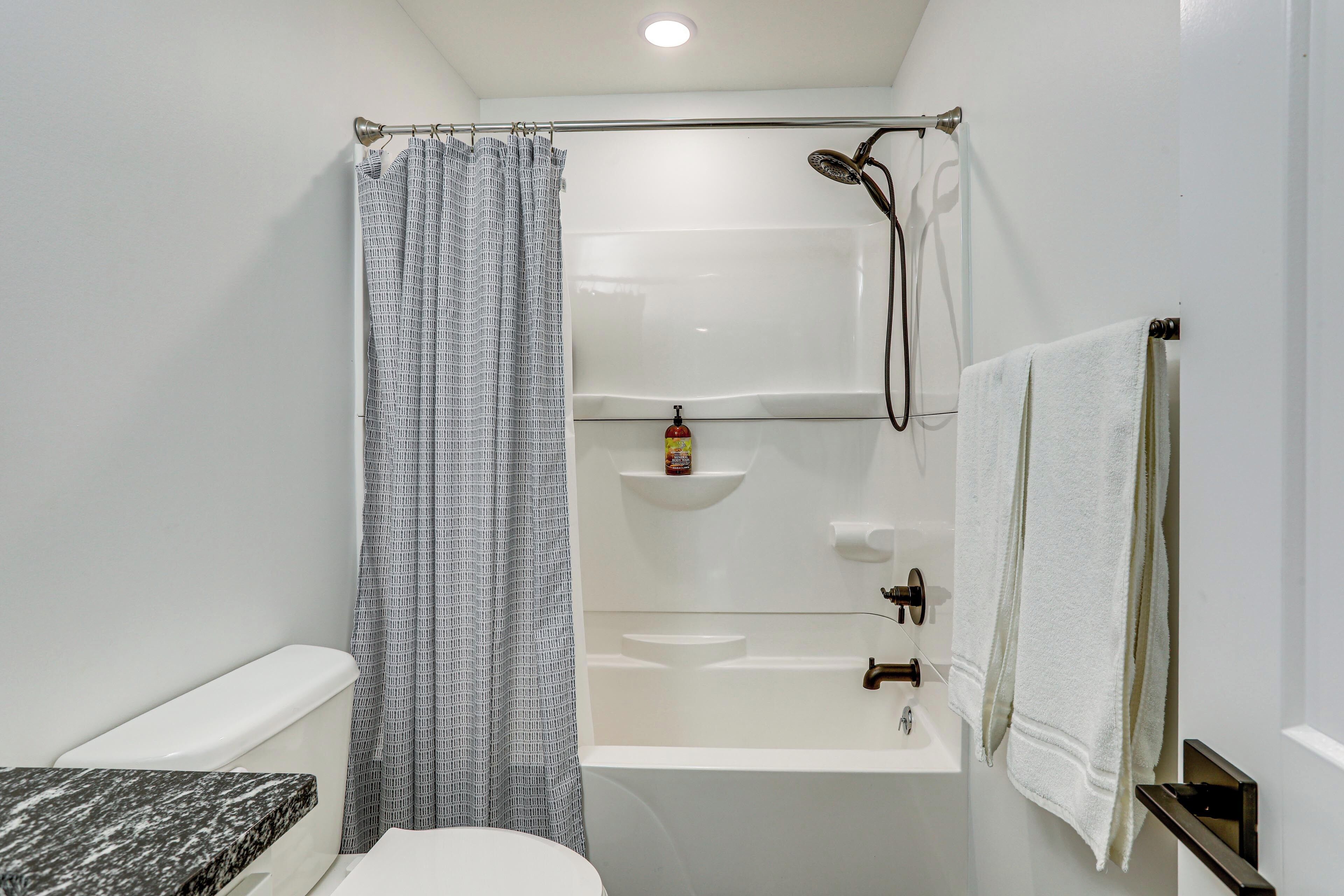 Une salle de bain comprenant des toilettes, un lavabo, une baignoire, une douche et un porte-serviettes.