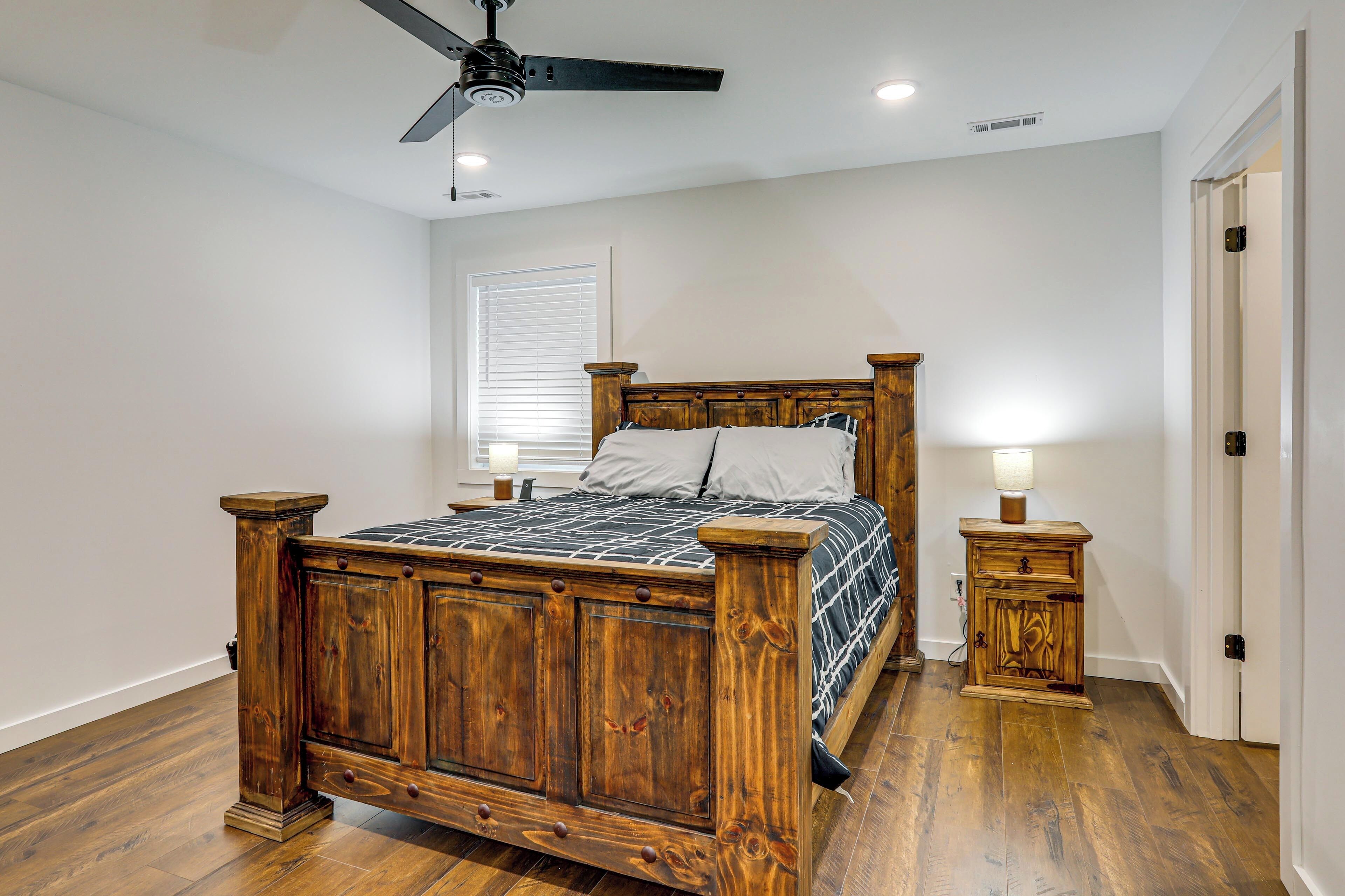 Une chambre à coucher avec un lit en bois, un ventilateur de plafond, une table de chevet et une fenêtre avec des stores.