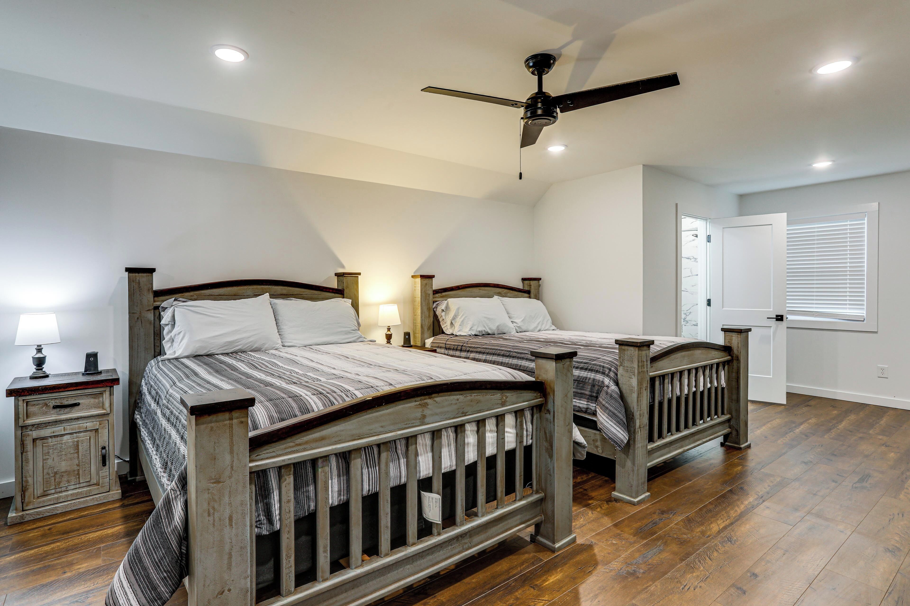 A bedroom with two wooden beds, a ceiling fan, and a nightstand with a lamp.