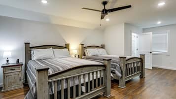 A bedroom with two wooden beds, a ceiling fan, and a nightstand with a lamp.