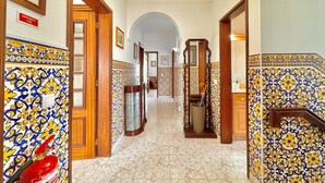 Um corredor com paredes revestidas de azulejos, portas de madeira e um extintor de incêndio.