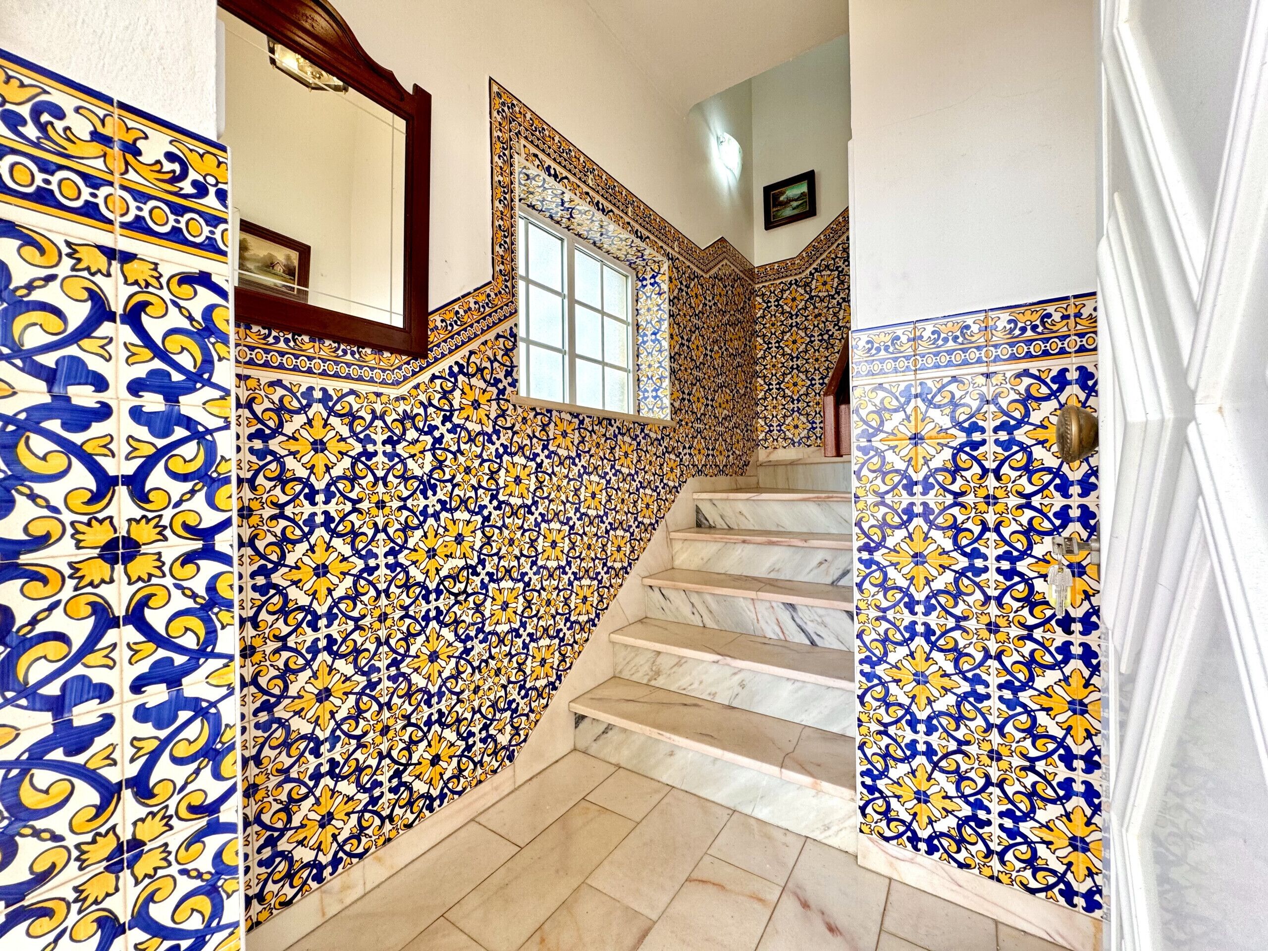 A staircase with ornate blue and yellow patterned tiles and marble steps.