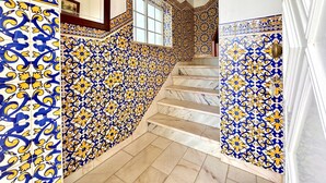Uma escadaria com azulejos ricamente decorados em azul e amarelo, além de degraus de mármore.