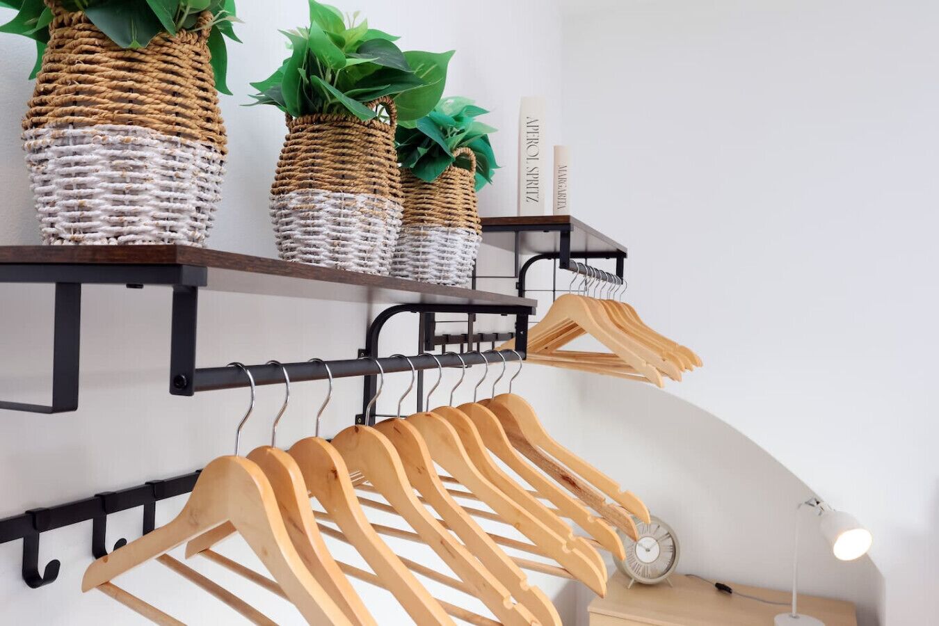 A room with a wooden coat rack, shelves with woven baskets, and a clock.