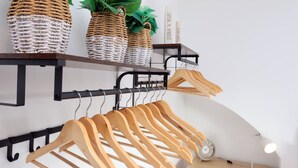 A room with a wooden coat rack, shelves with woven baskets, and a clock.