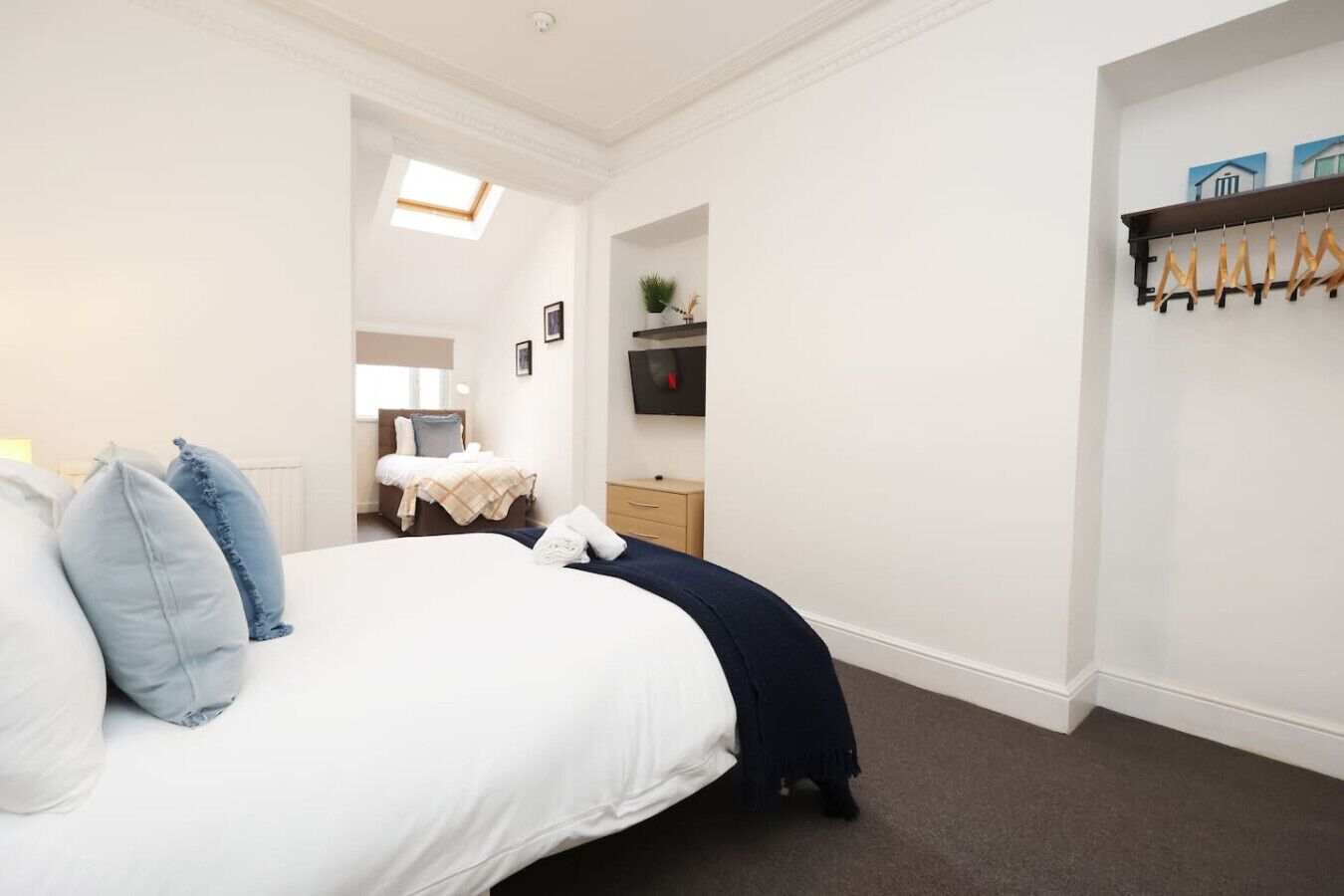A bedroom with a bed, a nightstand, a TV, and a coat rack.