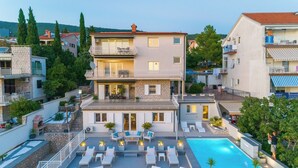 A multi-story building with a swimming pool, outdoor seating, and balconies. - Beautiful apartment near the beach with pool (Crikvenica)