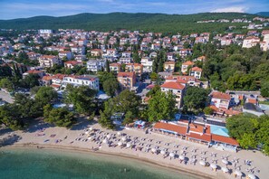 A coastal town with a beach, numerous buildings, and a hilly backdrop. - Beautiful apartment near the beach with pool (Crikvenica)