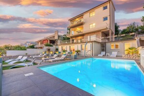 A modern two-story building with a swimming pool, lounge chairs, and a stone facade. - Beautiful apartment near the beach with pool (Crikvenica)