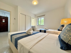 A hotel room with two beds, a window, a lamp, and a door. - ALBUFEIRA BALAIA GOLF VILAGE 8 WITH POOL by Homing (Albufeira)