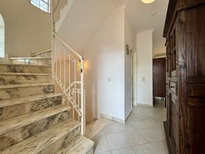A marble staircase leading to a second floor, a wooden door, and a tiled floor. - VILAMOURA SUMMER VILLA 3 WITH POOL by HOMING (Vilamoura)
