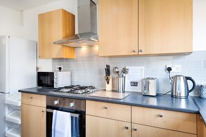 Eine moderne Küche mit Holzausstattung, einem Gasherd, einem Toaster und einem Wasserkocher.