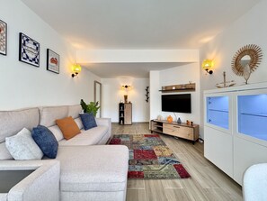 A modern living room with a sofa, TV, and decorative wall lights. - VILAMOURA CENTRAL BEACH  1  WITH POOL by HOMING (Vilamoura)