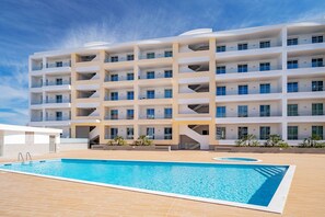 Ein mehrstöckiges Hotel mit Schwimmbad, Balkonen und einem modernen architektonischen Design.