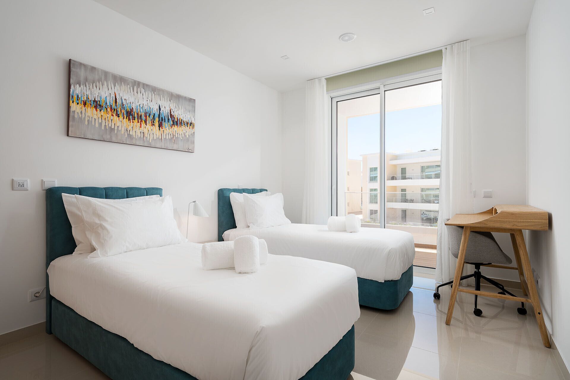 Une chambre d’hôtel avec deux lits, un bureau et une grande fenêtre.
