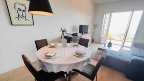 Zona pranzo con tavolo rotondo, sedie, televisore e divano.