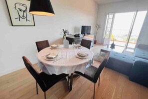 A dining area with a round table, chairs, a TV, and a sofa. - Golf Juan - Vallauris / Exceptional south-facing sea view (Vallauris)