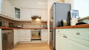 Una cucina con mobili bianchi, lavastoviglie, forno e frigorifero.