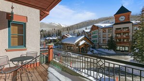 A hotel with a balcony, outdoor seating, and a view of a snowy mountain town. - 4208 - One Bedroom Standard Creekside Condominiums 1 Condo (Solitude)