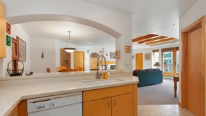 A modern kitchen with a dishwasher, wooden cabinets, and a large mirror. - 4208 - One Bedroom Standard Creekside Condominiums 1 Condo (Solitude)