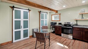 A kitchen with a dining table, chairs, cabinets, a stove, and a microwave. - Modern Arts District Loft With Boat Parking 1 Bedroom Cottage (Somerset)