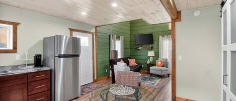 A kitchen with a stainless steel refrigerator, wooden cabinets, and a dining area with a glass table.