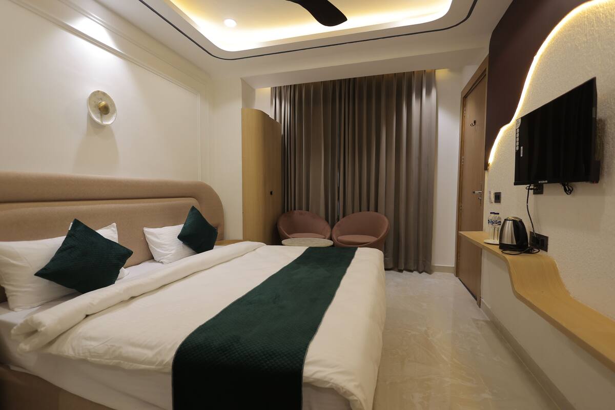 A hotel room with a bed, a TV, a desk, and a seating area.