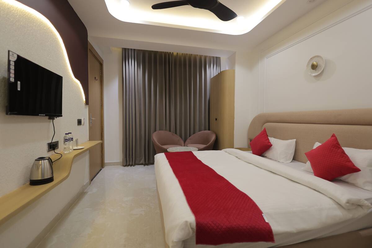 A hotel room with a bed, a TV, a coffee maker, a desk, and a chair.