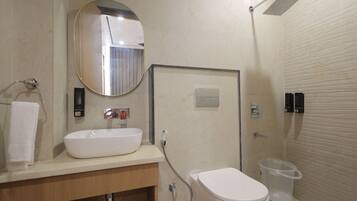 A bathroom with a white sink, a mirror, a toilet, and a shower.