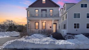 A two-story residential building with a balcony, a front porch, and a driveway with snow. - Pet Friendly Parks & Trails Pleasantville Home (Pleasantville)