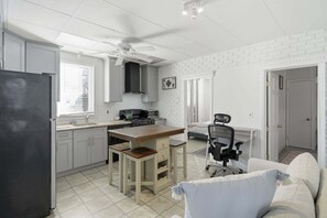 Uma cozinha compacta com geladeira, fogão, micro-ondas e uma área de jantar com mesa e cadeiras.