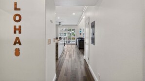 Un corridoio con pavimento in legno, pareti bianche e una ventola a soffitto.