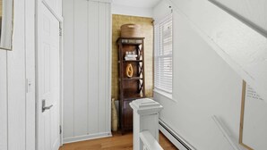 A hallway with a white door, a wooden cabinet with shelves, and a radiator.