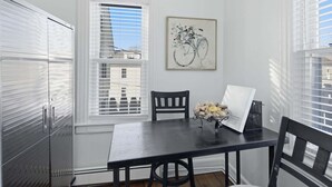 A dining area with a table, chairs, a vase with flowers, a framed picture, and a window with blinds. - Cozy Pleasantville Retreat Unit 2 2 Bedroom Apts (Pleasantville)