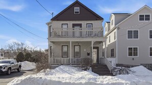 A two-story house with a balcony, a front porch, and a driveway. - Cozy Pleasantville Retreat Unit 2 2 Bedroom Apts (Pleasantville)