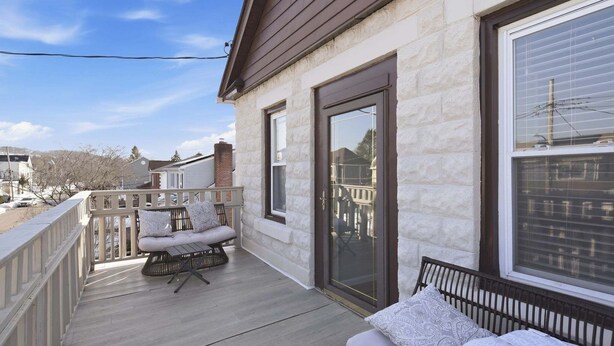 A covered porch with a seating area, a sliding glass door, and a view of the street. - Cozy Pleasantville Retreat Unit 2 2 Bedroom Apts (Pleasantville)