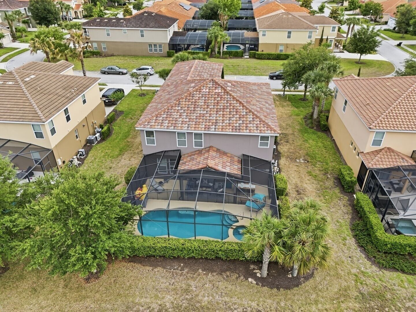 A residential area with houses featuring tiled roofs, a swimming pool, and surrounding greenery.