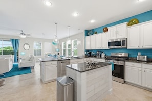 A modern kitchen with white cabinetry, a central island, stainless steel appliances, and pendant lighting. - St4119ot Solterra Resort 6 Bedroom Home (Davenport)