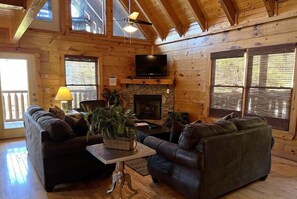A log cabin interior with a fireplace, a television, and a seating area. - Airport Runway 33 3 Bedroom Cabin (Pigeon Forge)