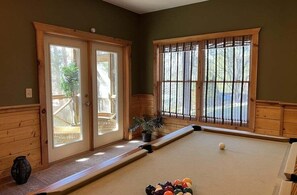 A pool table in a room with wooden walls and large windows. - Airport Runway 33 3 Bedroom Cabin (Pigeon Forge)
