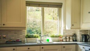 A kitchen with a window, a sink, and a coffee maker. - Maple Lodge (Knighton)