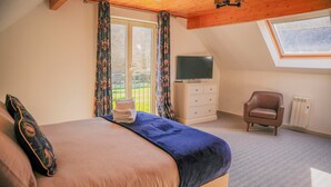 A bedroom with a bed, a chair, a TV, and a window. - Maple Lodge (Knighton)