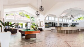 A spacious indoor area with a pool table, large windows, and a reception desk. - Charming 2-bedroom Apartment in Sosua With Pool View (Sosúa)