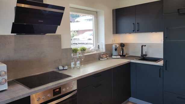 A modern kitchen with a built-in oven, a coffee maker, and a window with a view of the outside.