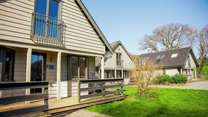 Een tweelaags huis met een balkon, een veranda en een kleine tuin.