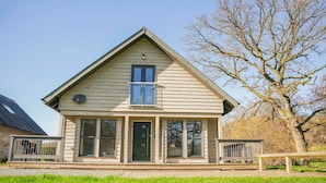 A two-story house with a front porch, a large window, and a door. - Oak Lodge (Knighton)