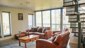 A spacious living room with a sectional sofa, a wooden coffee table, and a staircase. - Oak Lodge (Knighton)
