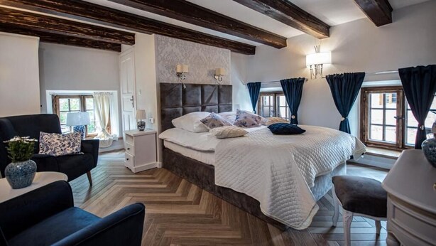Un dormitorio con una cama grande, una mesita de noche, una silla y un aparador.